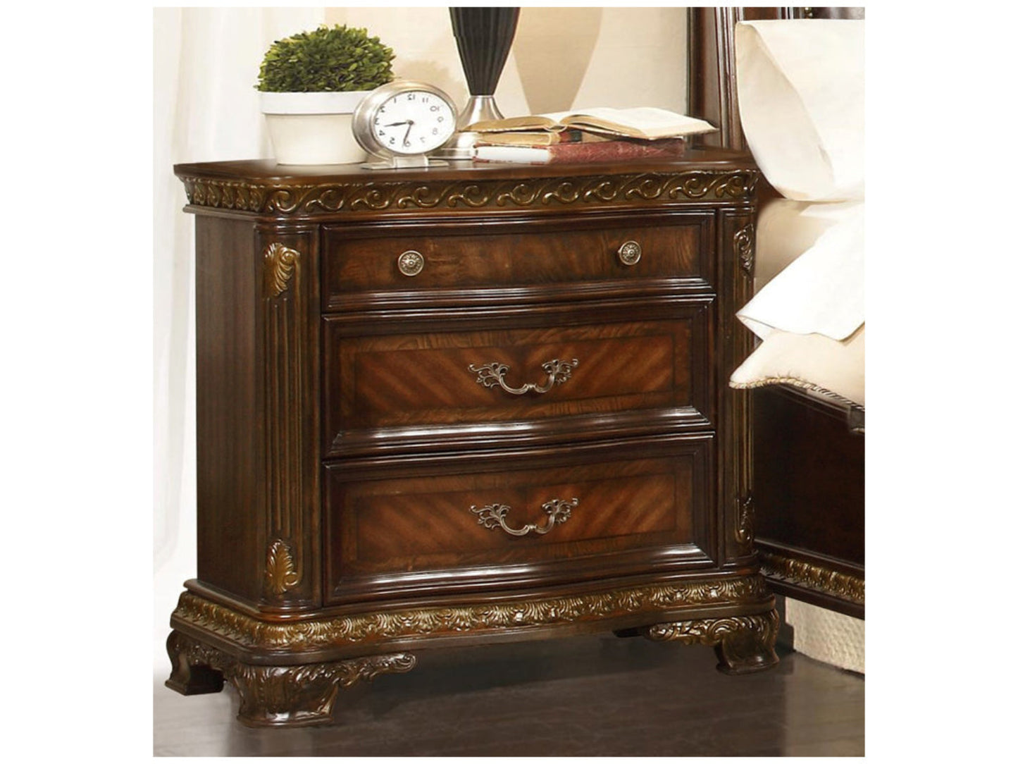 Wooden nightstand with decorative carvings and gold accents, featuring a clock and books on top.